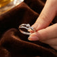 Silver ring with a diamond held by a hand on a brown fabric background