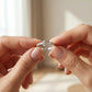 Close-up of hands holding a silver ring with a blurred background