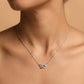 Silver necklace with a heart-shaped pendant on a person against a beige background