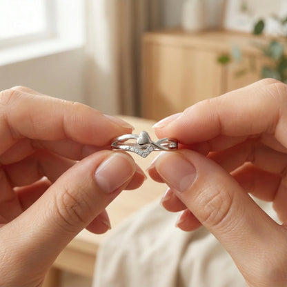 Close-up of hands holding a silver ring with a heart design.