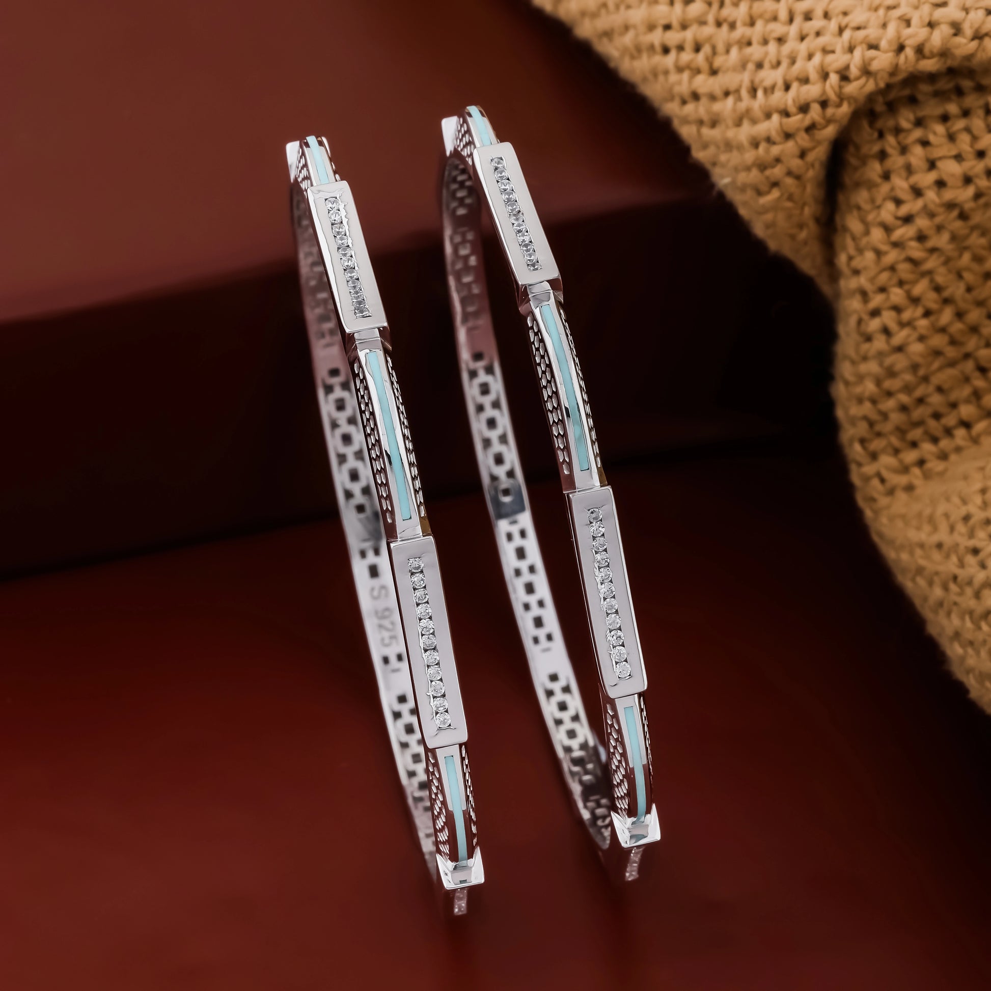 Pair of silver hoop earrings with engraved text on a brown surface