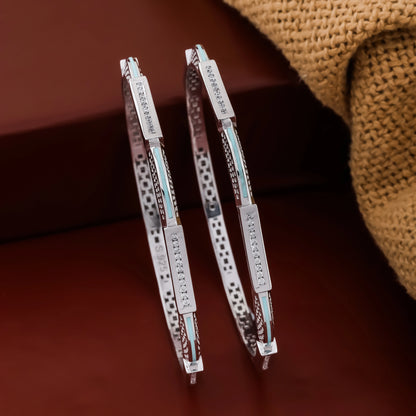 Pair of silver hoop earrings with engraved text on a brown surface