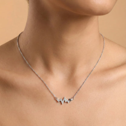 Silver necklace with a unique design on a person's neck against a beige background