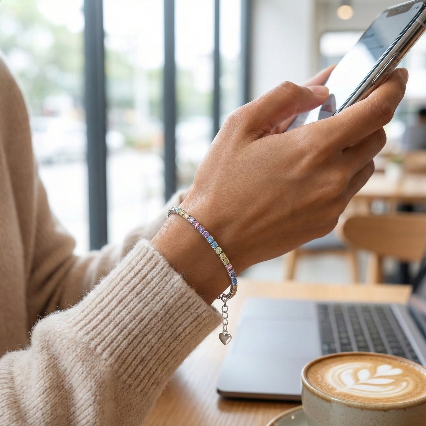 Person using a smartphone with a laptop and coffee in a cafe setting