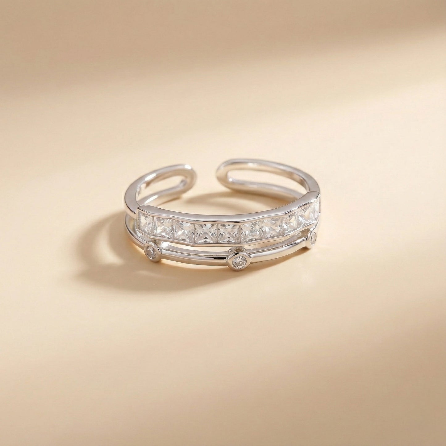 Silver ring with embedded diamonds on a beige background