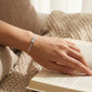Hand wearing a bracelet on an open book with a soft, warm background