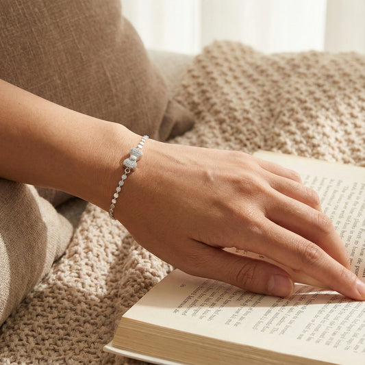 Hand wearing a bracelet on an open book with a soft, warm background