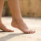 Close-up of a foot wearing a colorful beaded anklet on a blurred natural background