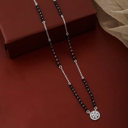 Necklace with black beads and a silver pendant on a brown surface