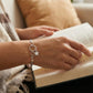 Person reading a book with a bracelet on a blurred background
