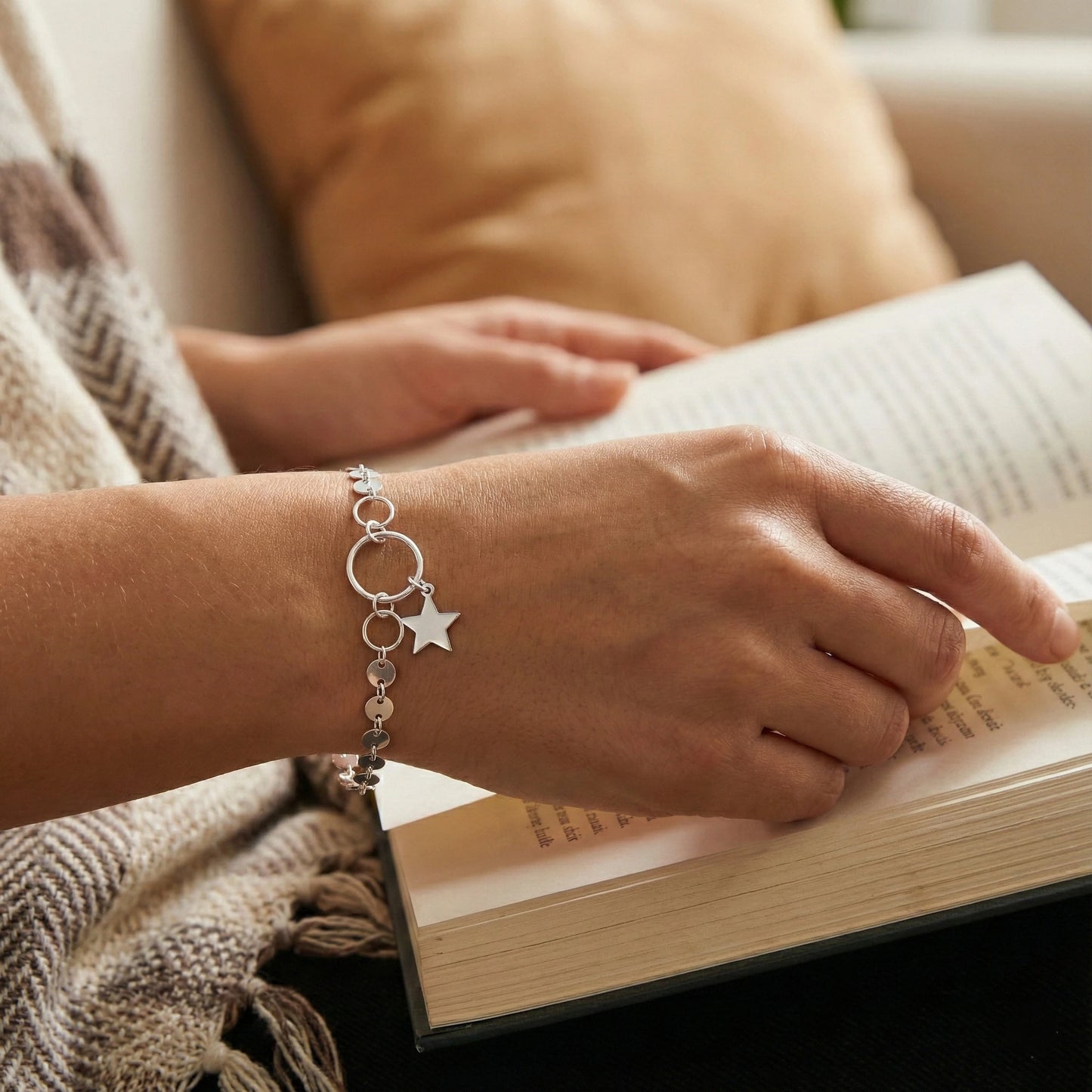 Person reading a book with a bracelet on a blurred background