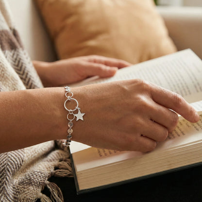 Person reading a book with a bracelet on a blurred background