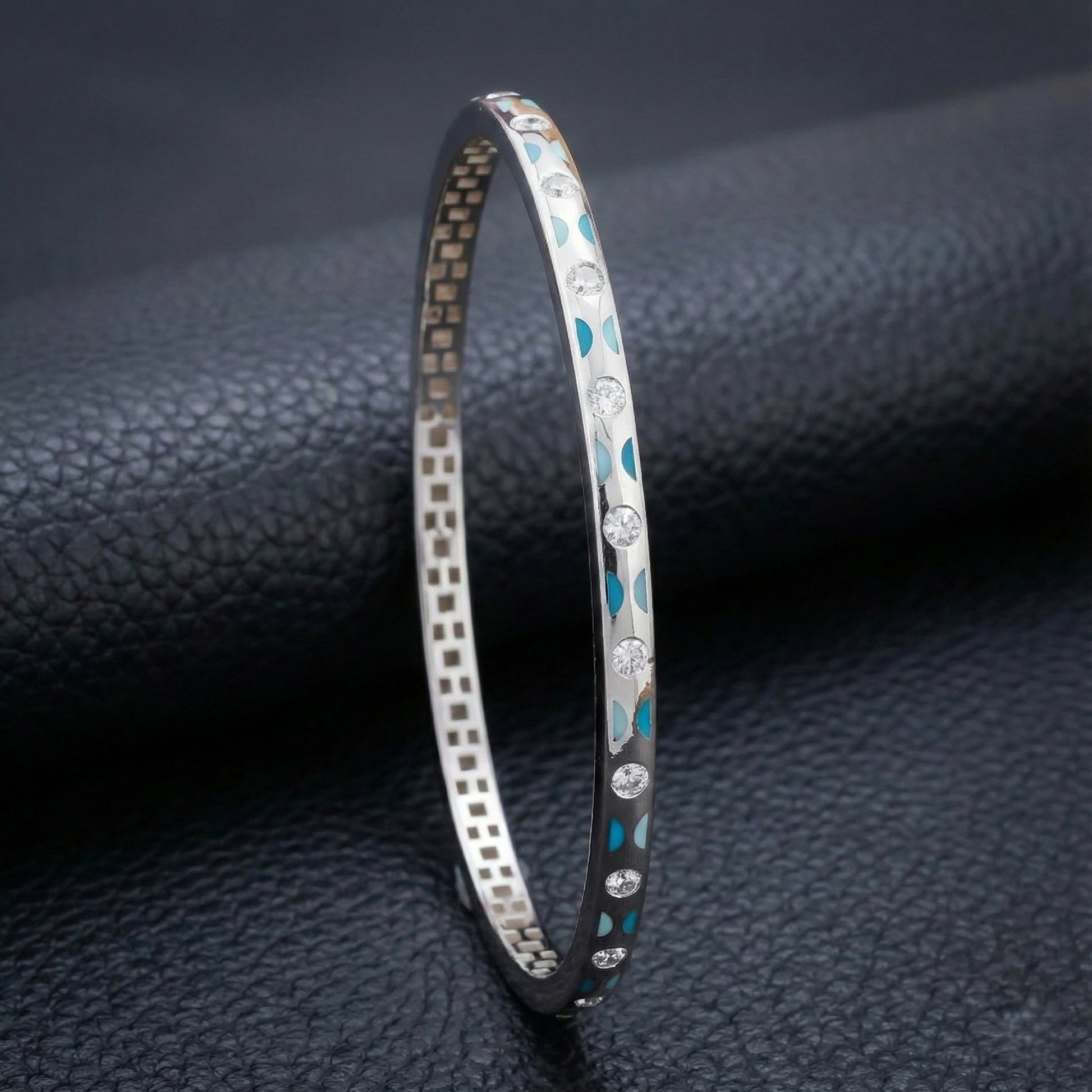 Silver bracelet with blue accents on a dark textured surface