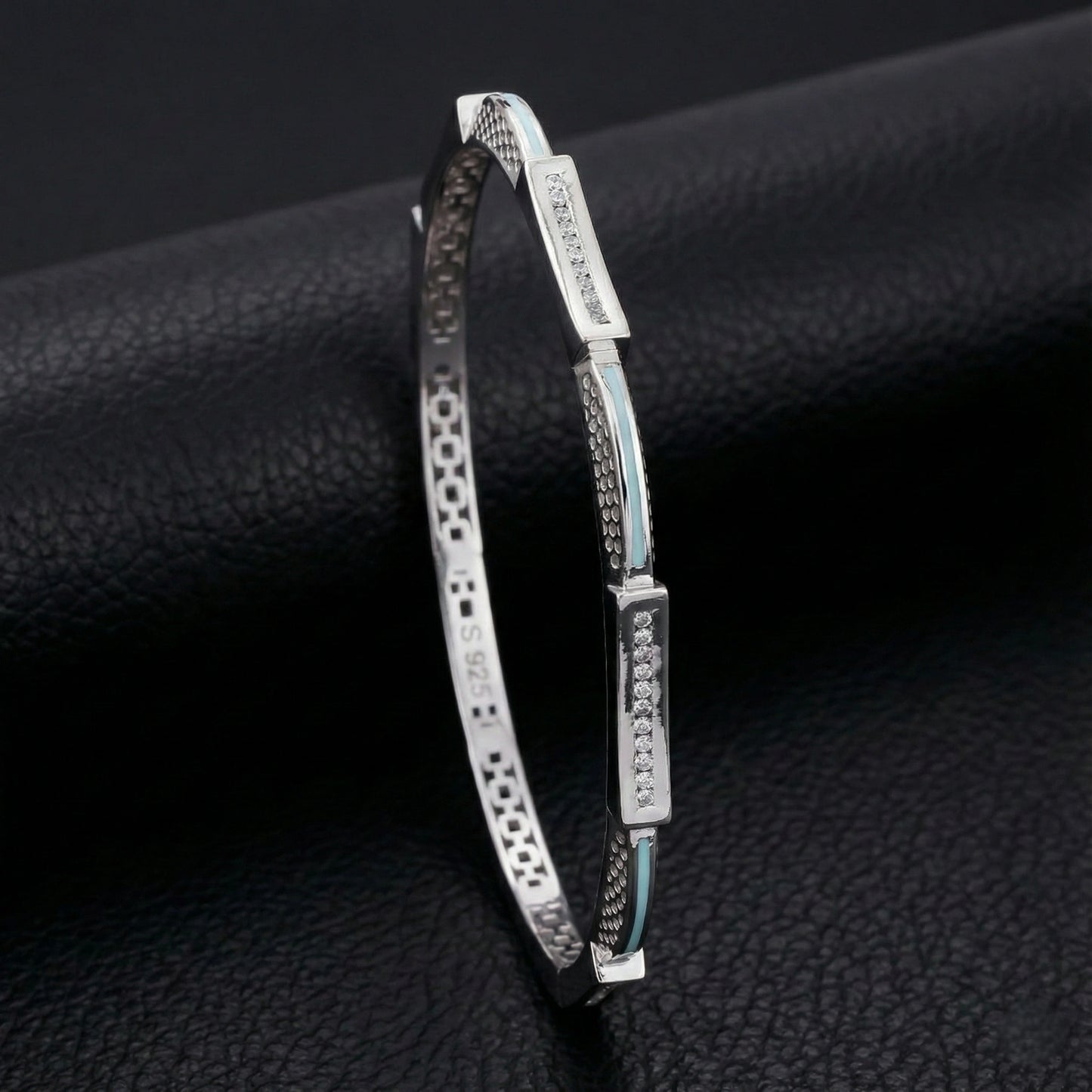 Silver bracelet with decorative elements on a black textured surface