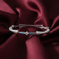 Silver bracelet with blue accents on a burgundy fabric background