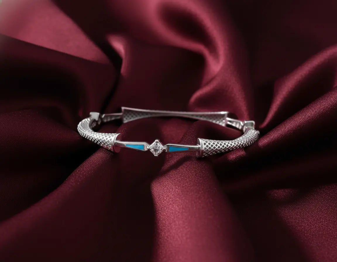 Silver bracelet with blue accents on a burgundy fabric background