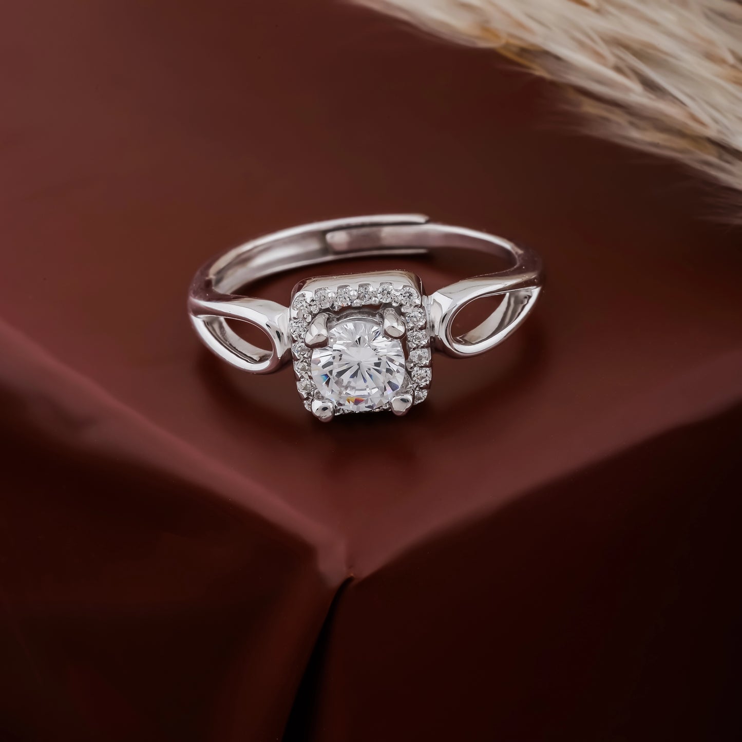 Silver ring with a diamond on a brown fabric background