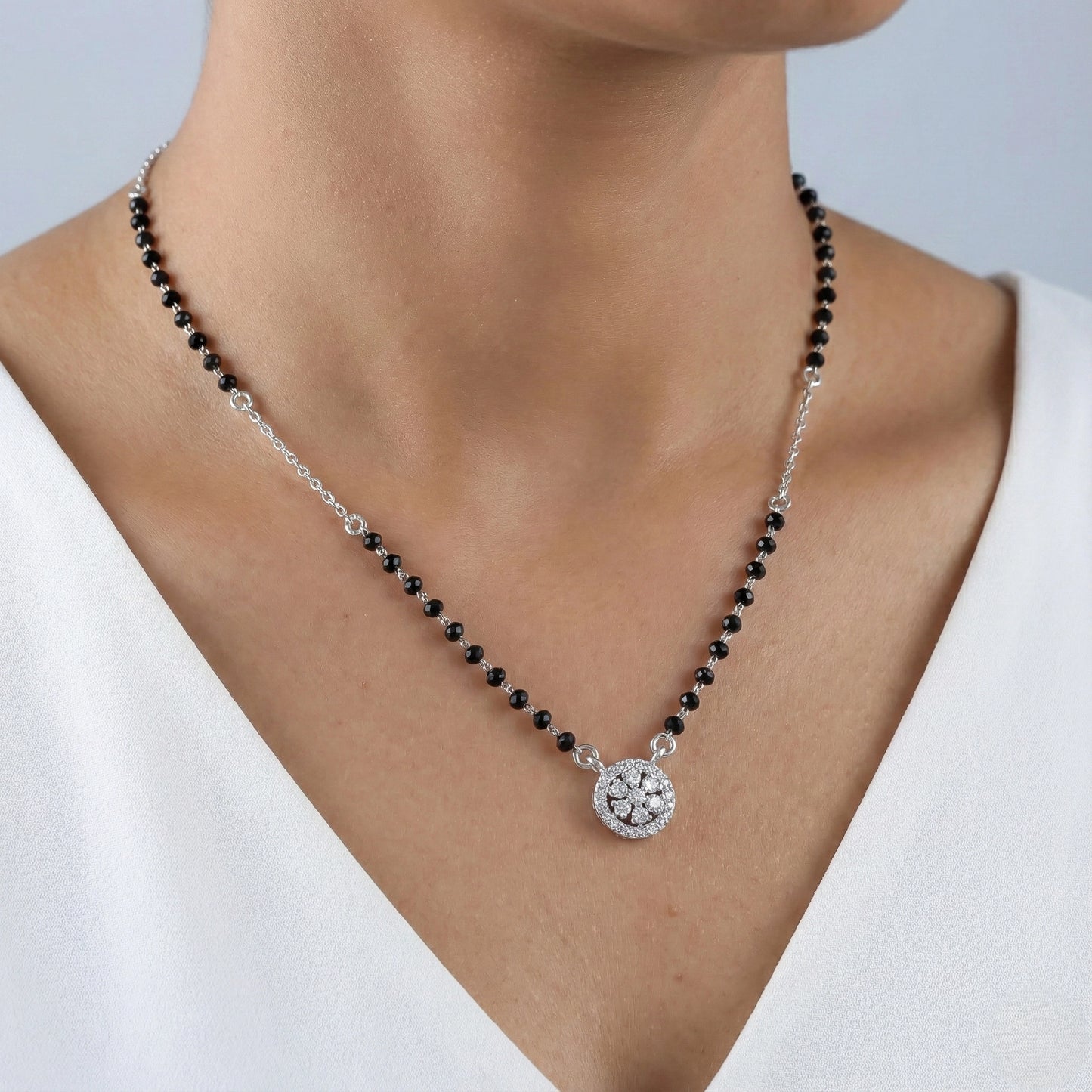 Necklace with black beads and a silver clasp on a person wearing a white top.