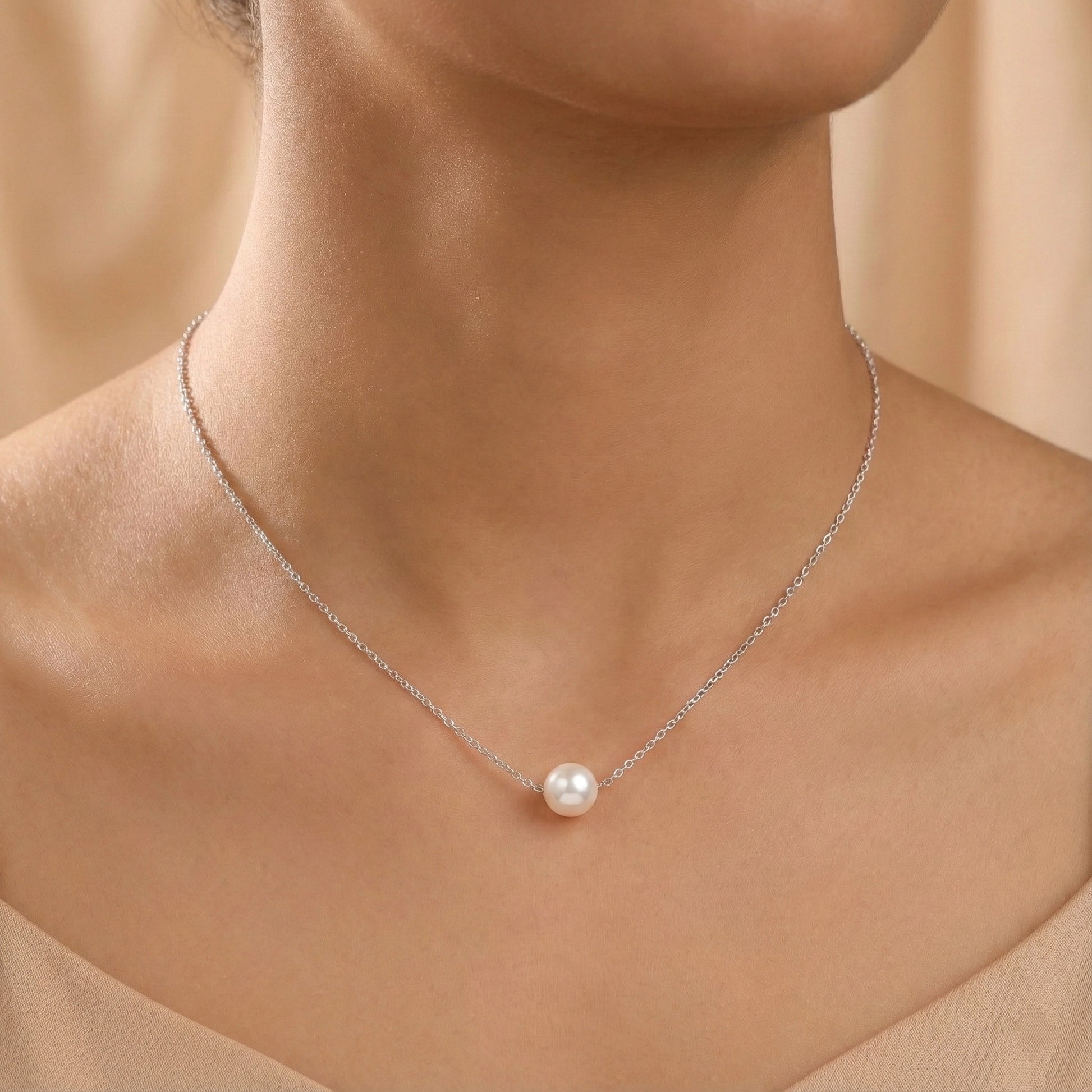 Pearl necklace on a model against a beige background