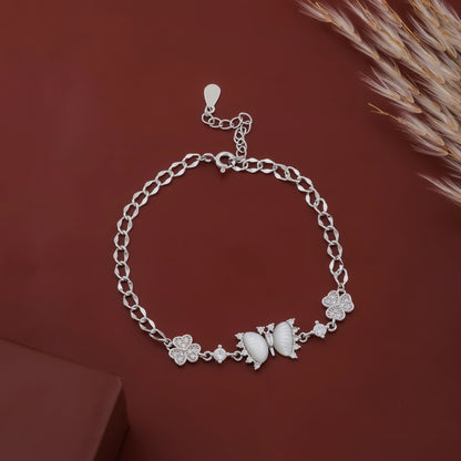 Silver bracelet with butterfly and flower designs on a brown background