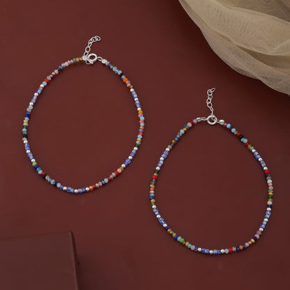 Two beaded necklaces on a dark red surface with a beige fabric in the background.