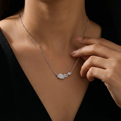Silver necklace with leaf pendant worn by a person against a dark background