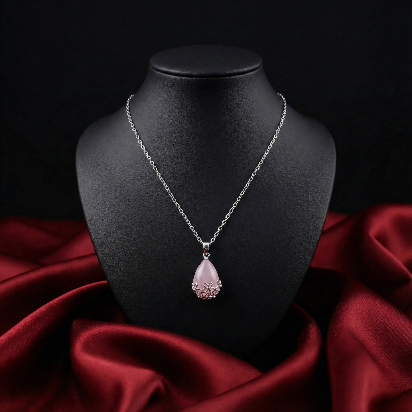 Necklace with a pink pendant on a black mannequin bust against a red fabric background