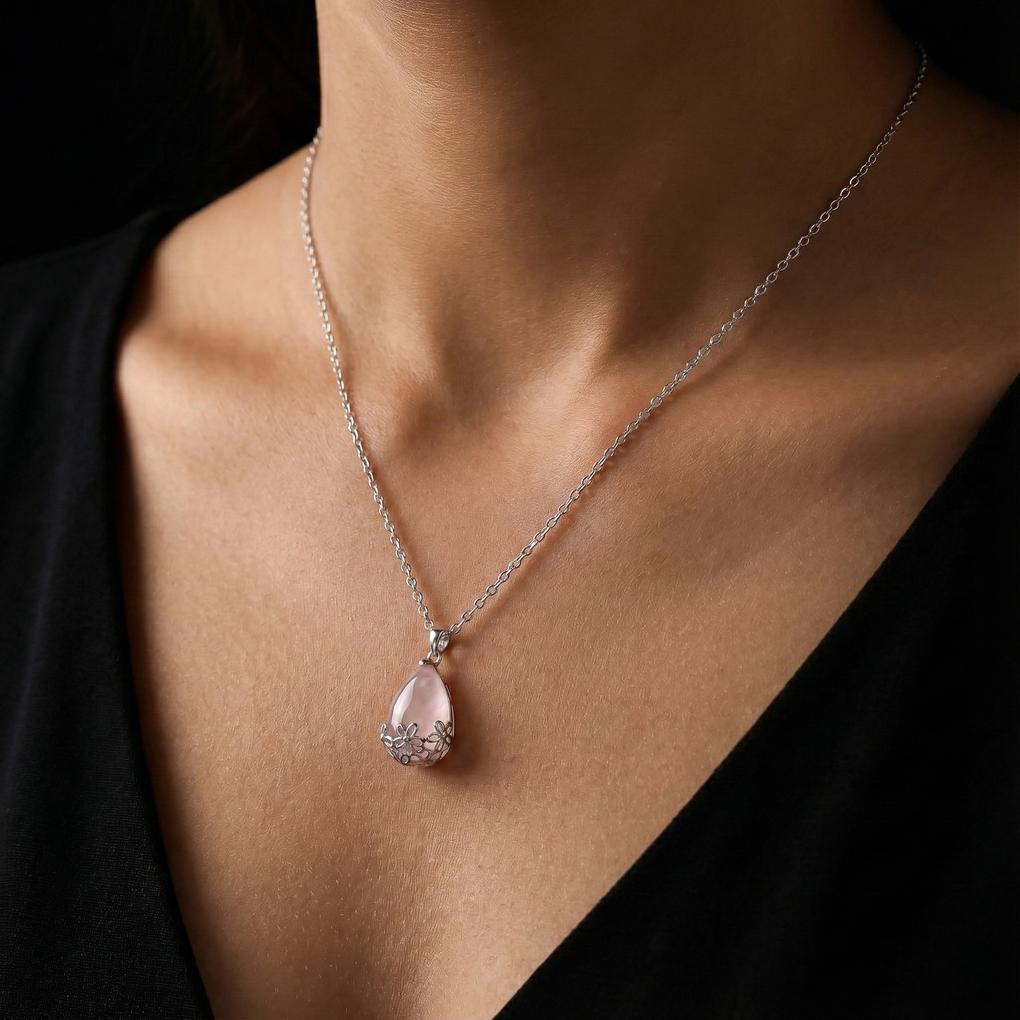 Necklace with a pink teardrop pendant on a person wearing a black top.