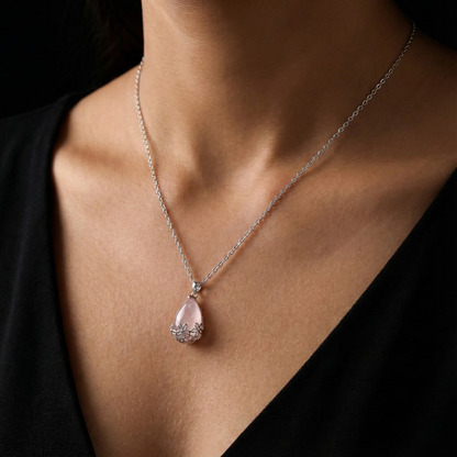 Necklace with a pink teardrop pendant on a person wearing a black top.