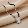 Necklace with black beads and a silver pendant on a beige fabric background