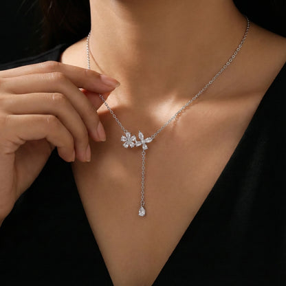 Silver necklace with a pendant worn by a person against a black background