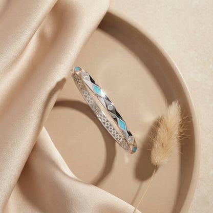 Silver bracelet with turquoise stones on a beige fabric background