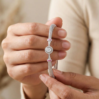 Close-up of a hand holding a silver bracelet with a pink accent