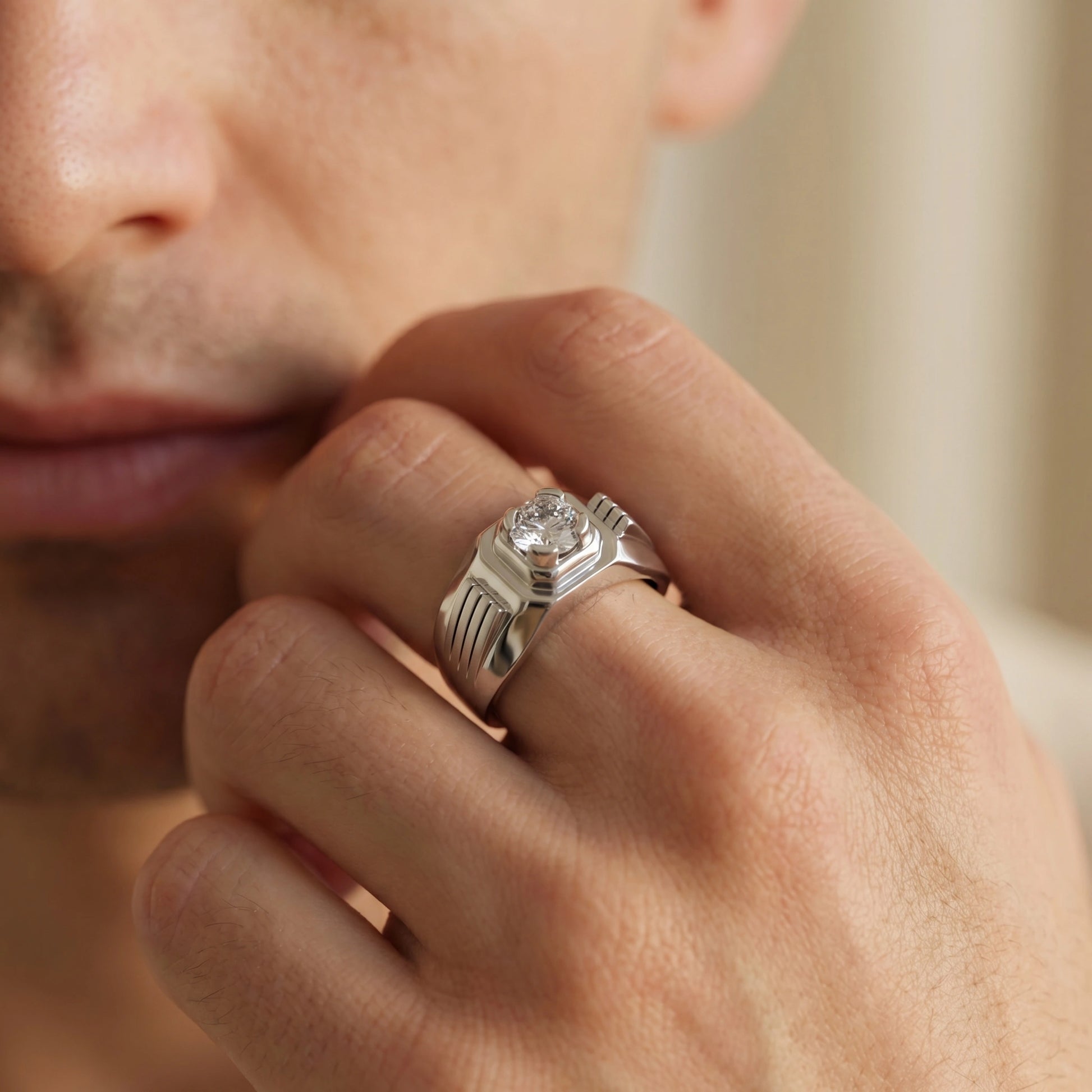 Close-up of a hand wearing a silver ring with a diamond, blurred background
