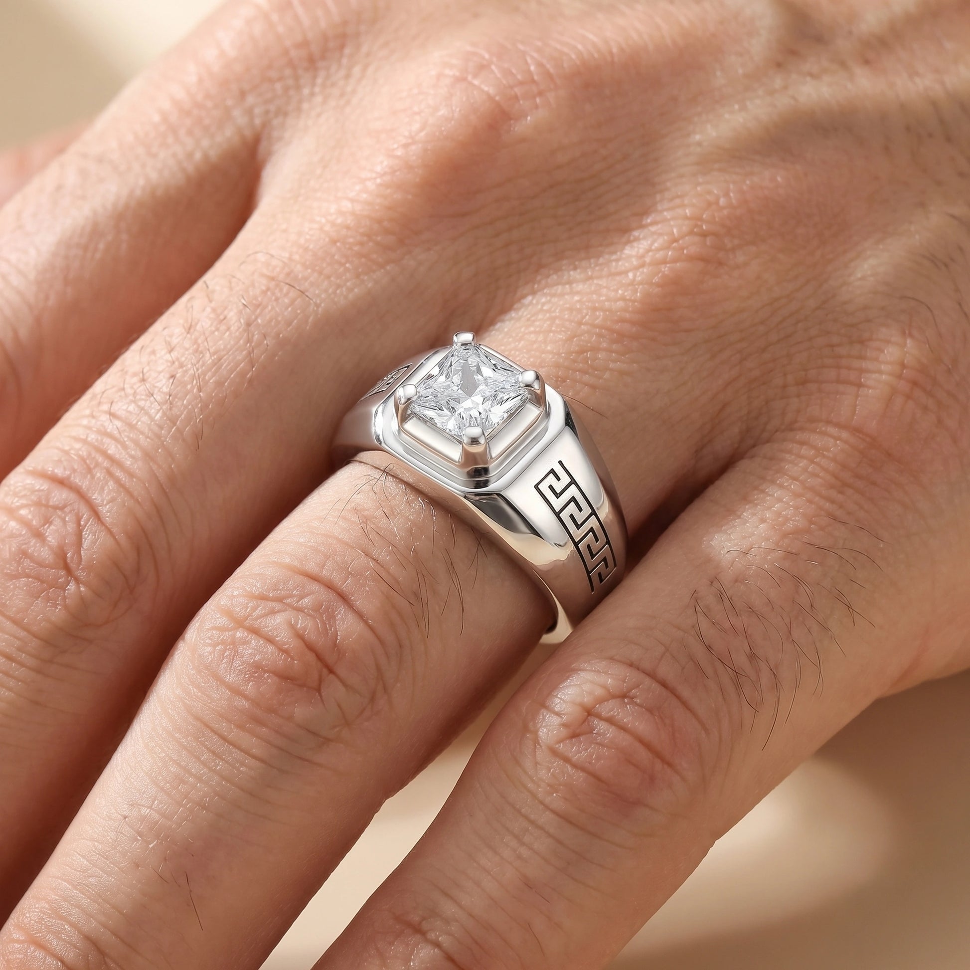 Silver ring with a diamond on a person's finger against a neutral background