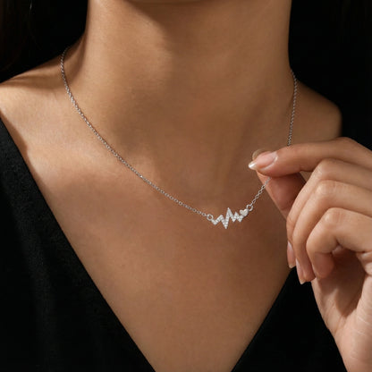 Necklace with a unique design held by a hand against a neutral background