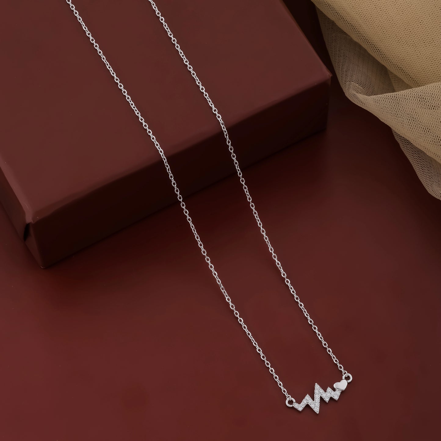 Silver necklace with a heartbeat design on a brown surface
