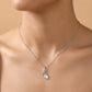 Silver necklace with a leaf pendant on a person's neck against a beige background