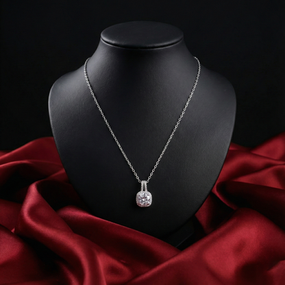 Silver necklace with a pendant on a black mannequin bust against a red fabric background