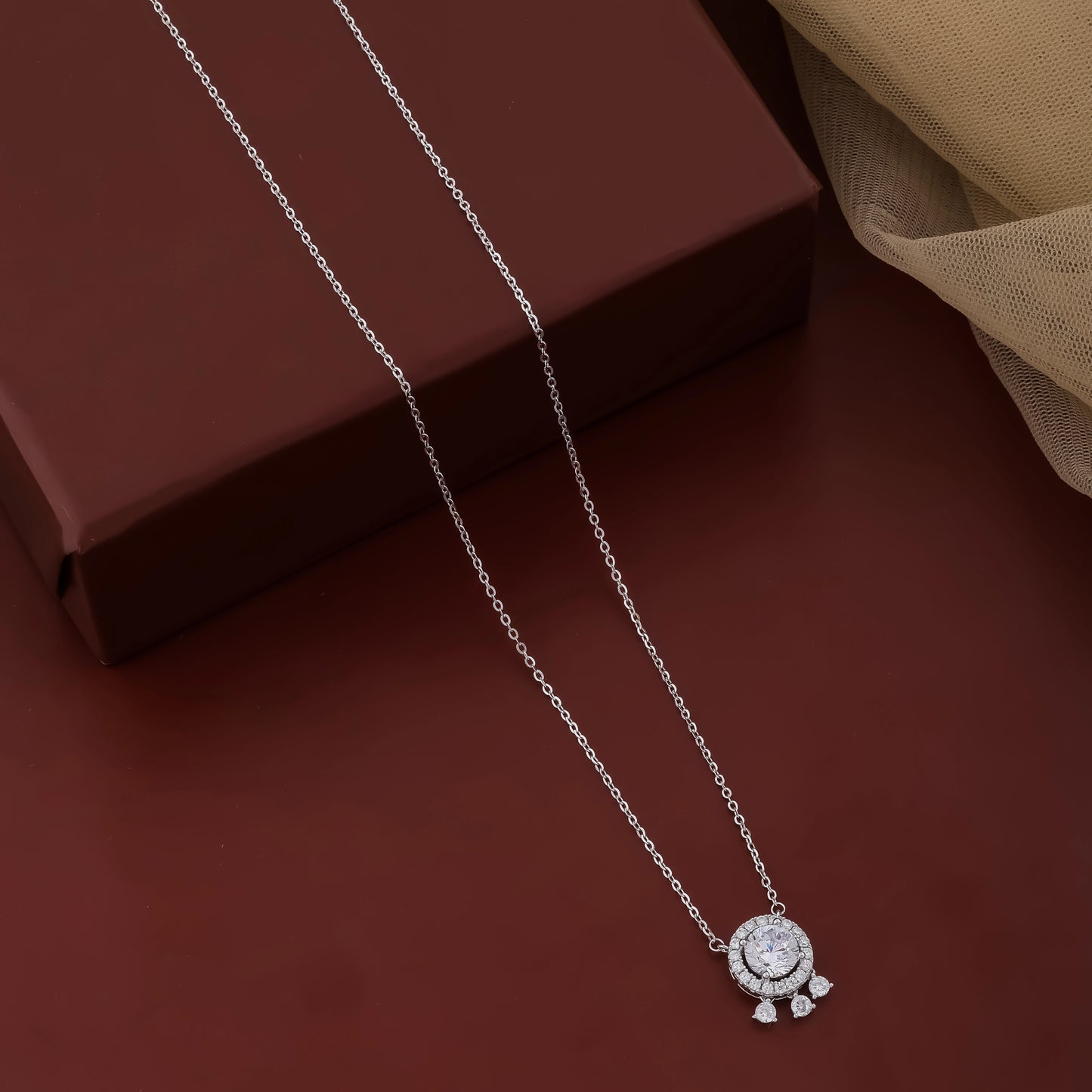 Silver necklace with a pendant on a dark brown surface