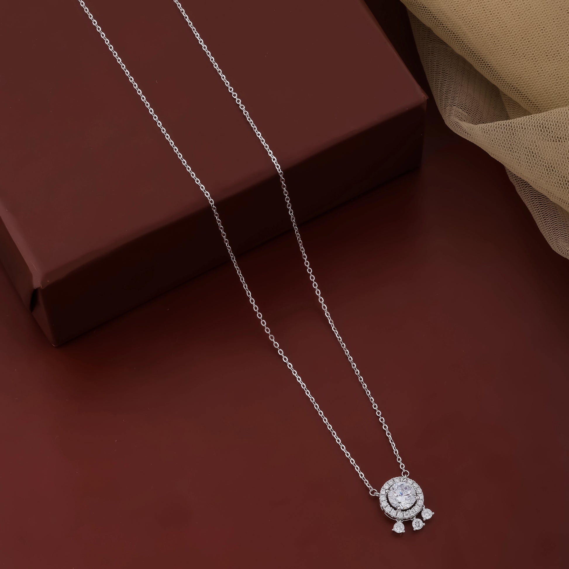 Silver necklace with a pendant on a dark brown surface