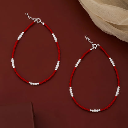 Two red beaded necklaces with white beads on a brown background