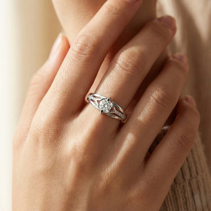 Close-up of a hand wearing a silver ring with a diamond on a neutral background
