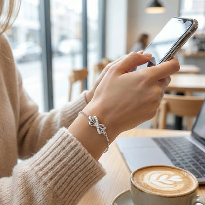 Person using a smartphone with a cup of coffee and laptop in a cafe setting