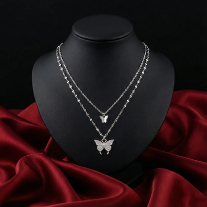 Silver butterfly necklace on a black mannequin bust with a red fabric background