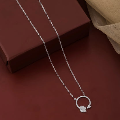 Silver necklace with a circular pendant on a dark red surface