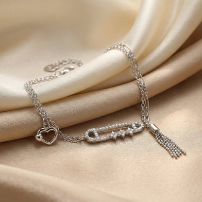 Silver bracelet with heart charm and tassel on beige fabric