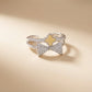 Silver bow-shaped ring with a yellow center on a beige background