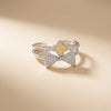 Silver bow-shaped ring with a yellow center on a beige background