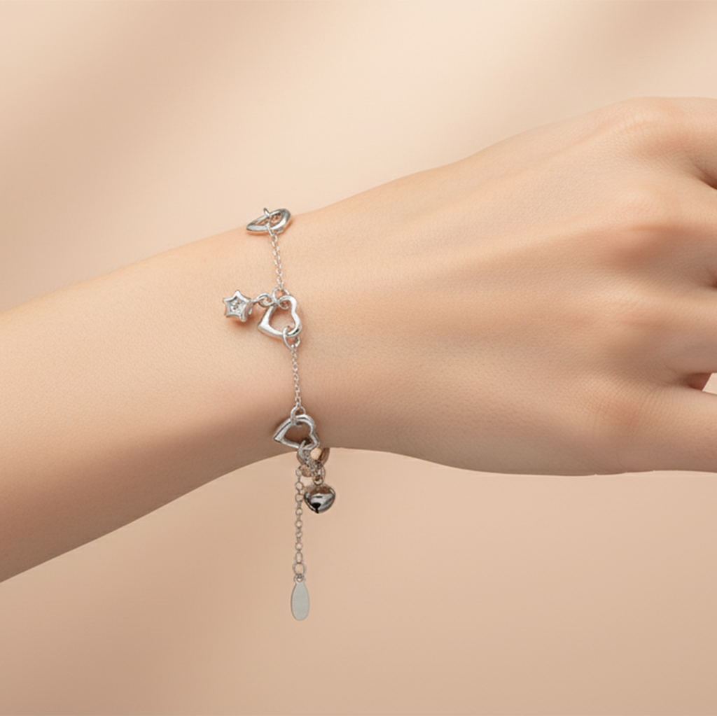 Silver bracelet with heart-shaped charms on a wrist against a beige background